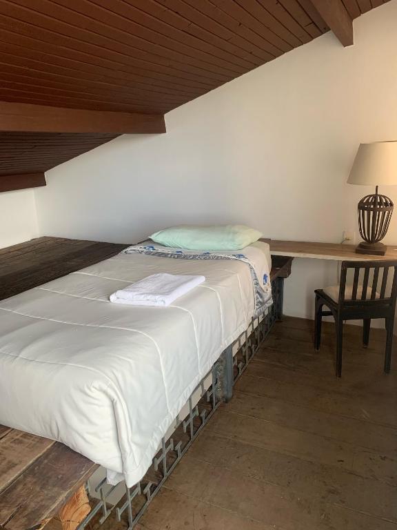 a bed in a room with a table and a chair at Canto do Sossego in Oliveira