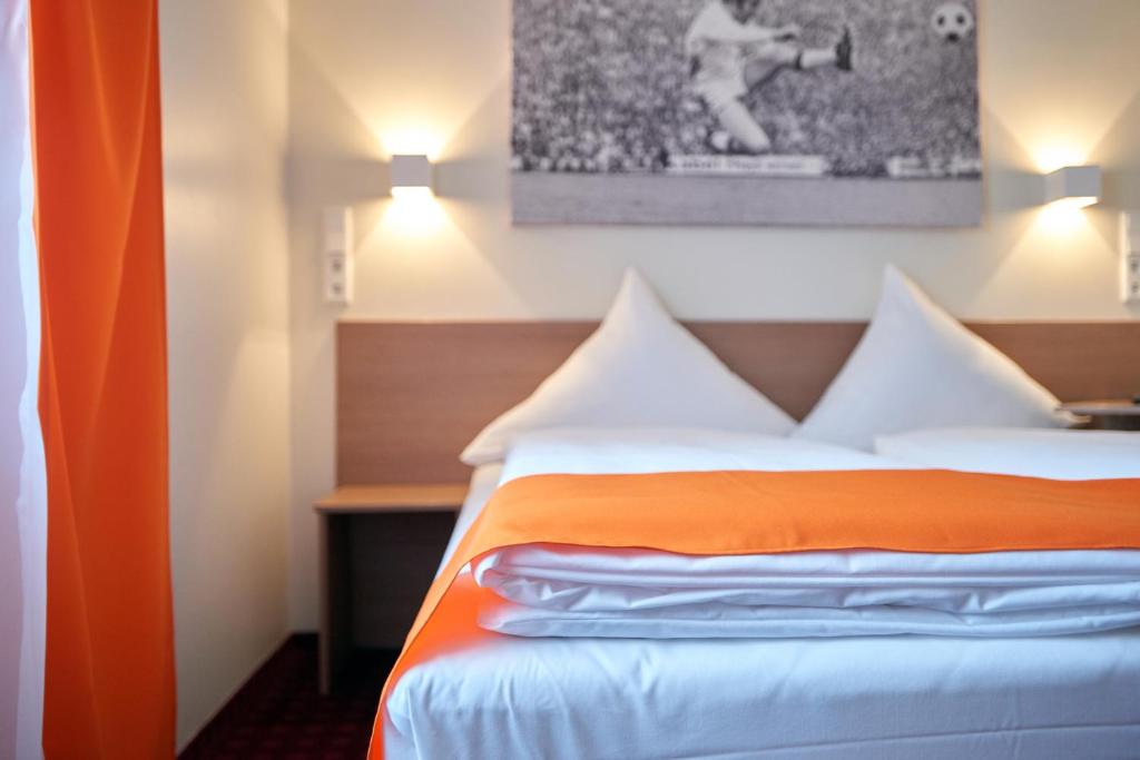 Habitación de hotel con cama con cortina naranja en McDreams Hotel Mönchengladbach, en Mönchengladbach