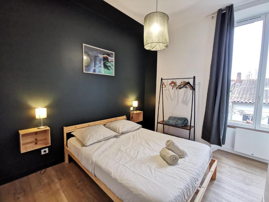 une chambre avec un lit avec un mur noir dans l'établissement Cocon Verde Appartement T2, à Cognac