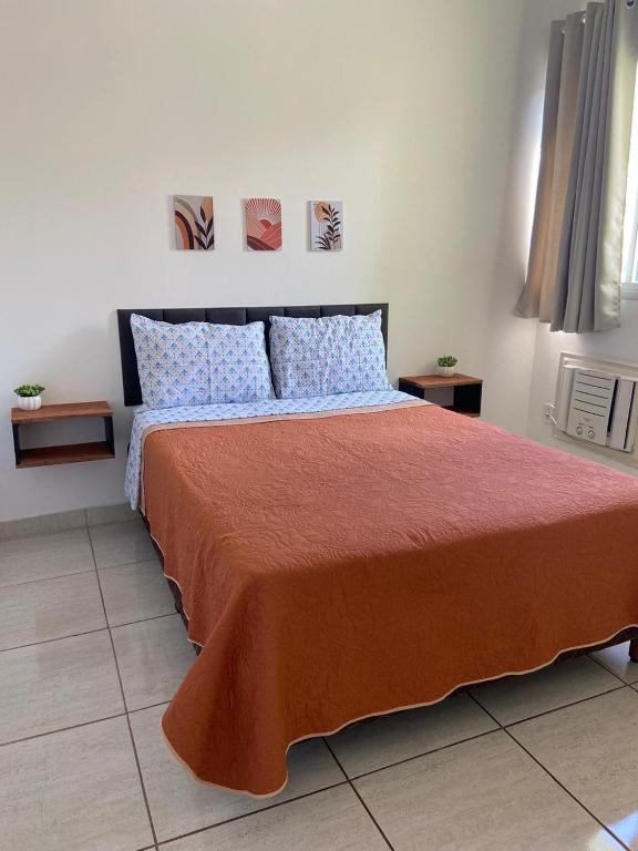 a bedroom with a large bed with orange blanket and blue pillows at Ap sossegado na Praia do Canto in Vitória