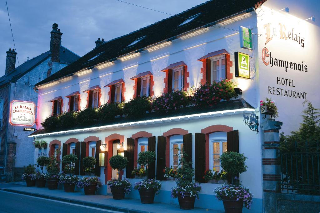 a white building with potted plants in front of it at Logis Le Relais Champenois in Sézanne