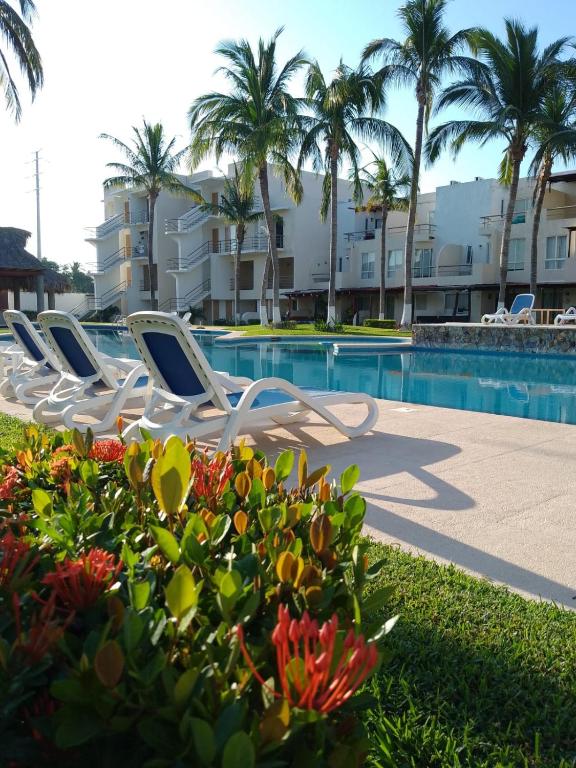 Eine Reihe weißer Liegestühle neben einem Schwimmbecken in der Unterkunft Hermosa Villa con recamara en PB in Acapulco