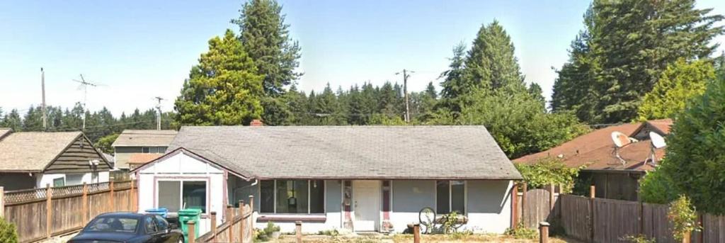 a house with a fence and a car in a yard at Dog Friendly Cozy Remodeled Shoreline Rambler in Shoreline
