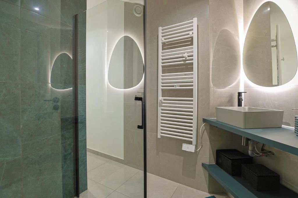 La salle de bains est pourvue d'une douche, d'un lavabo et d'un miroir. dans l'établissement Superbe Appartement 1 chambre avec clim, terrasse et parking, à Montpellier