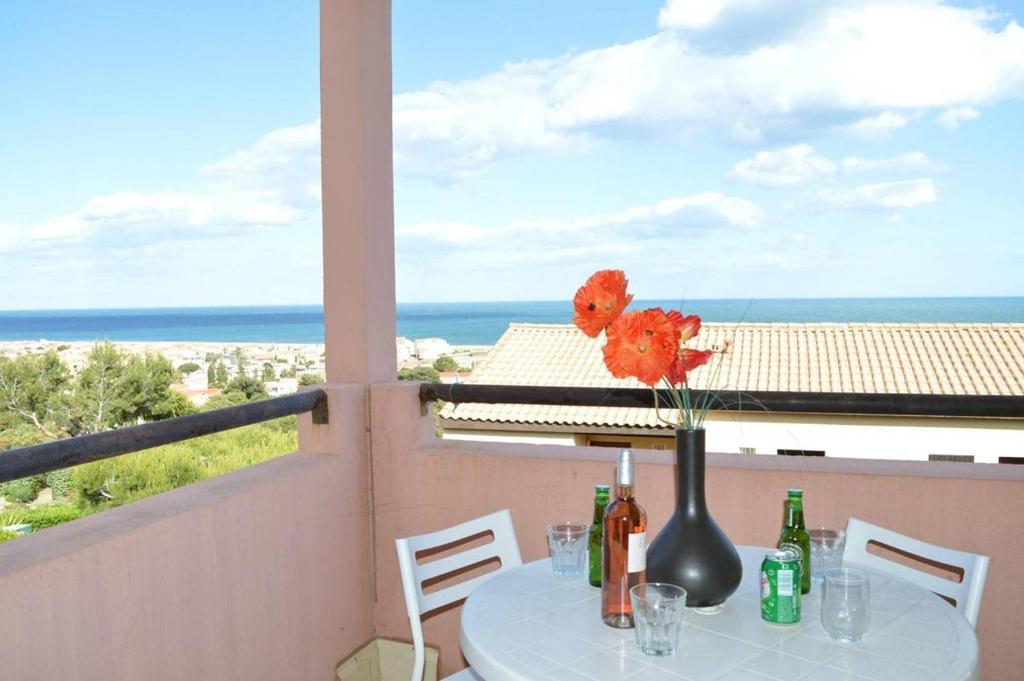 une table avec un vase de fleurs sur un balcon dans l'établissement SP280-124 Appt Studio Cabine 4 couchages SAINT PIERRE LA MER, à Saint Pierre La Mer