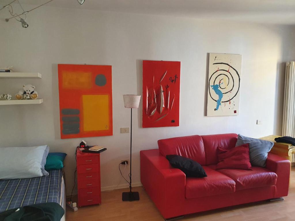 ein Wohnzimmer mit einem roten Sofa und einigen Gemälden in der Unterkunft A casa di Giò e Lorenzo- Appartamento via Guidelli in Reggio nell'Emilia