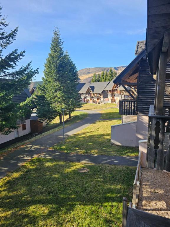 une maison avec un arbre sur le côté d'une route dans l'établissement App 2 chambres SuperBesse 35m2 4 à 6 personnes proches Lacs et commerces, à Besse-et-Saint-Anastaise