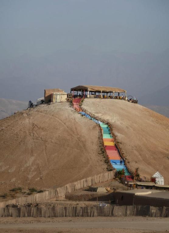 a hill with a rainbow colored river on it at La Dune Agafay Desert Camp in Marrakech