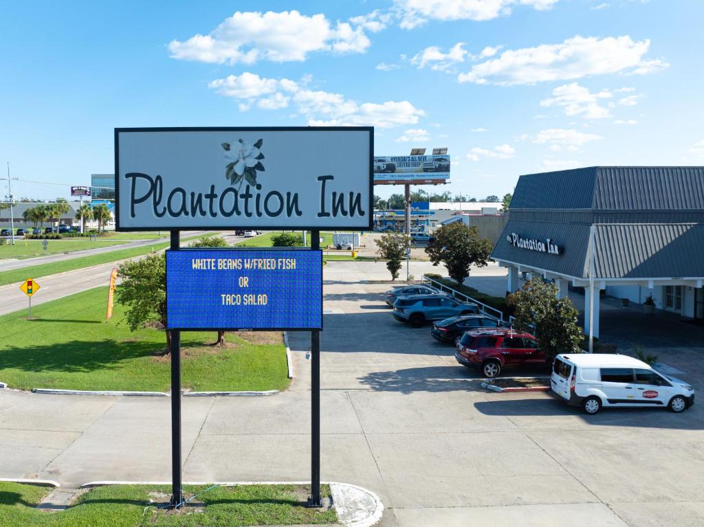 a sign in front of a parking lot with cars at Plantation Inn in Houma