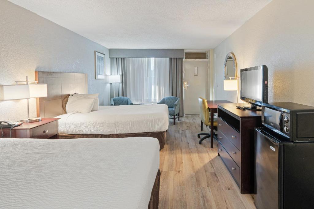 a hotel room with two beds and a flat screen tv at Plantation Inn in Houma