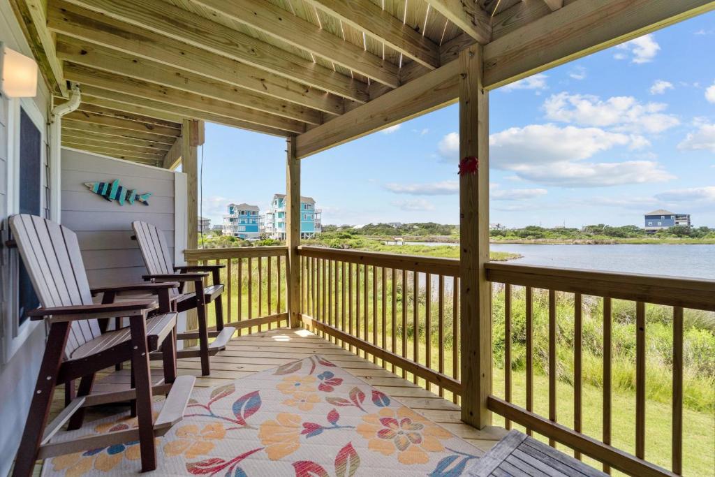 a porch with two chairs and a view of the water at Finn's Up in Hatteras