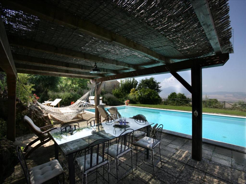 un patio con mesa, sillas y piscina en Agriturismo Fonte Senesi, en Monticchiello