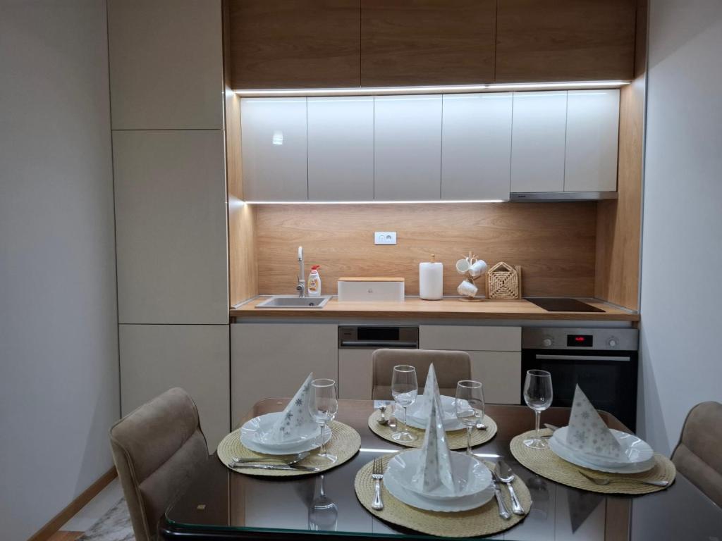 una cucina con tavolo, piatti e bicchieri da vino di Gala Lux Lazarevac a Lazarevac