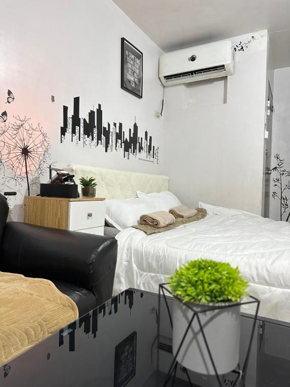 a bedroom with two beds and a couch and a plant at Affordable Condo in Cebu in Cebu City