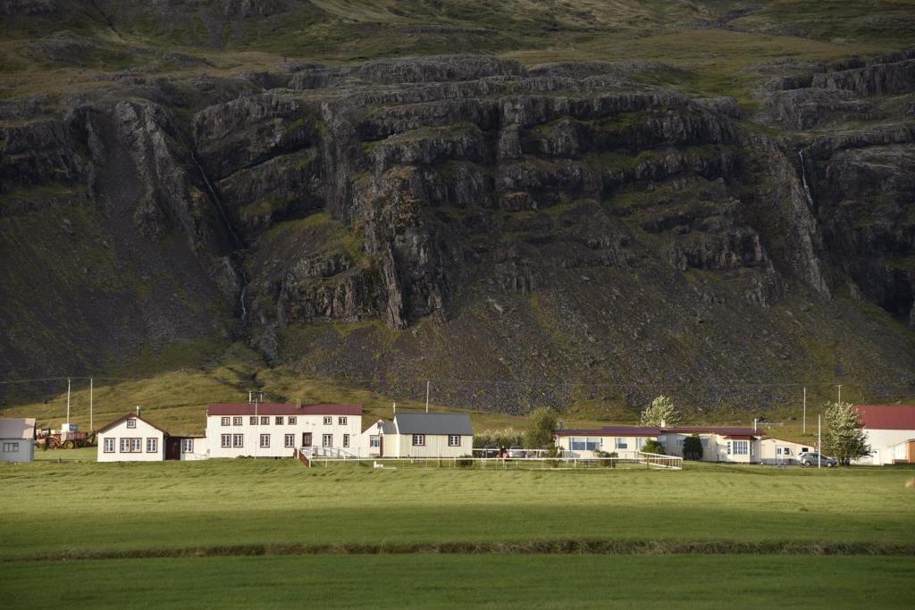 a field with houses and a mountain in the background at Berunes HI Hostel in Berunes