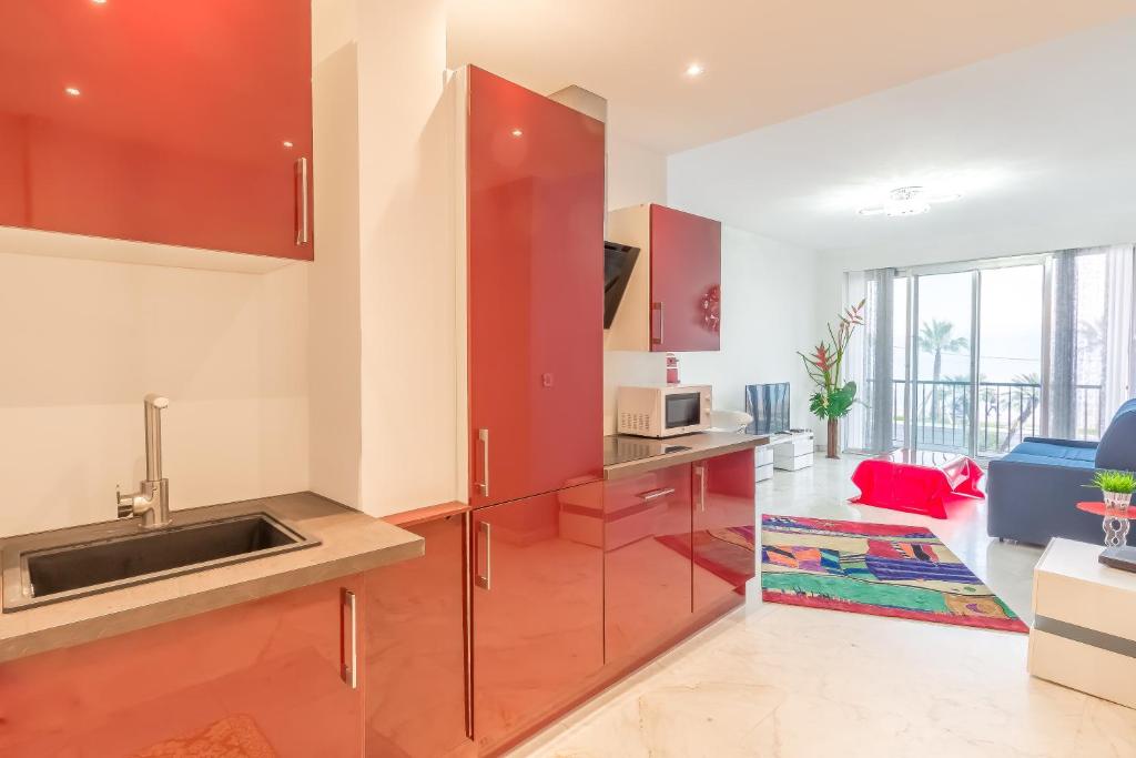 une cuisine avec des armoires rouges et un évier dans l'établissement Nice promenade des anglais vue mer, à Nice