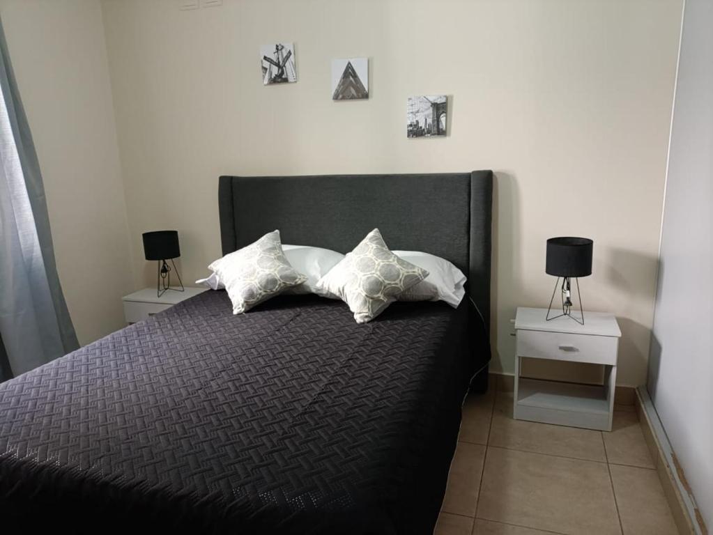 a bedroom with a black bed with three pillows at Talcahuano in Guaymallen