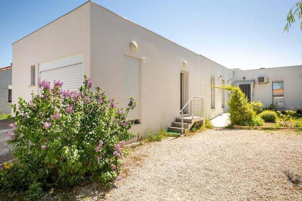 un bâtiment blanc avec des fleurs devant dans l'établissement Logement 2 chambres tout confort Nimes, à Nîmes
