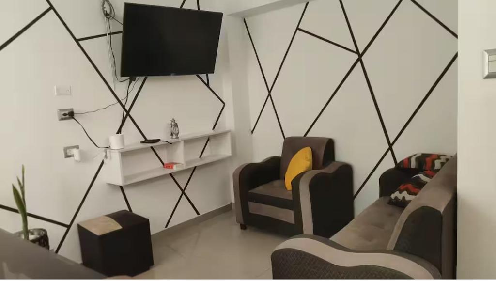 a living room with two chairs and a flat screen tv at MINI DPTO 302 PISO 3 - Consultar Cochera in Tacna