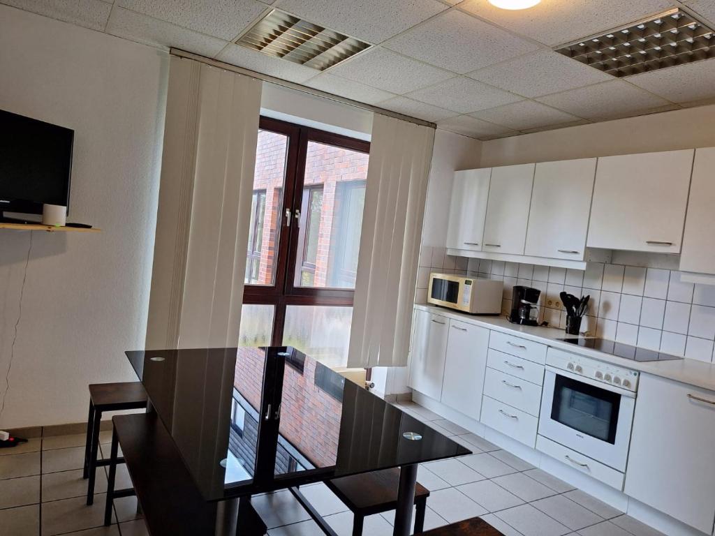 een keuken met witte kasten en een zwarte tafel en een tafel sidx sidx sidx bij Gästezimmer 2 in Mönchengladbach