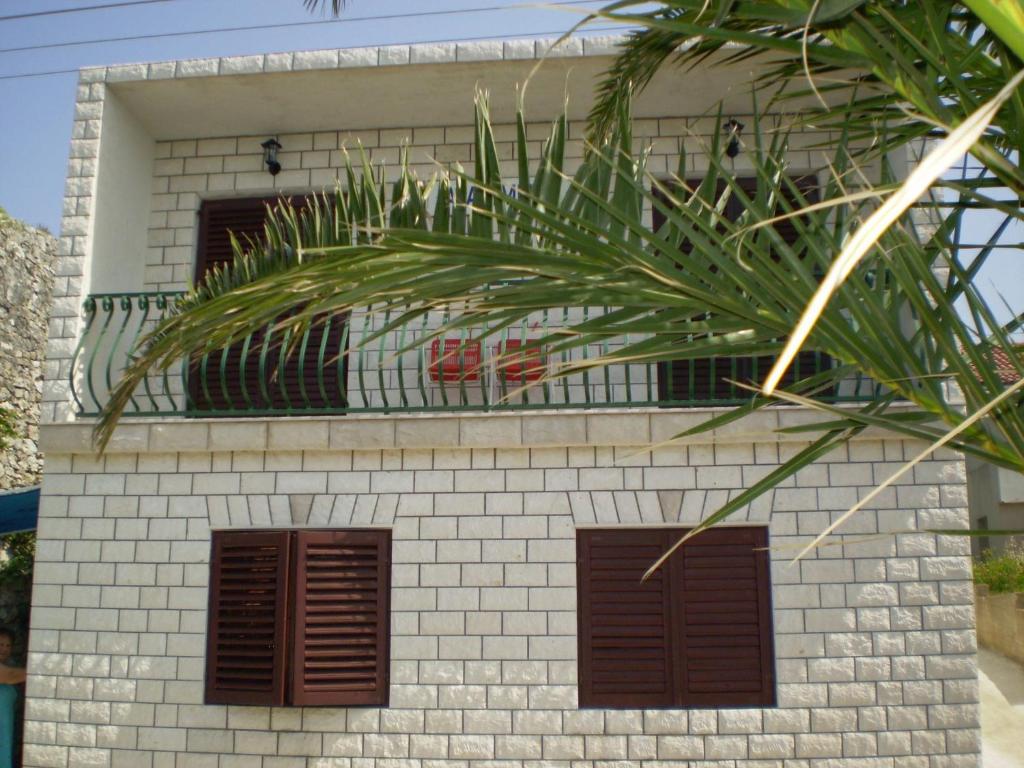 a white brick building with brown windows and a balcony at Apartment Smil in Sućuraj