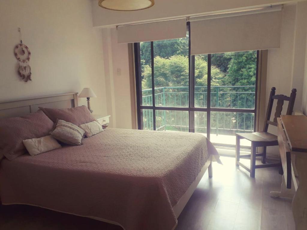 a bedroom with a bed and a large window at Cuatro Estaciones in San Carlos de Bariloche