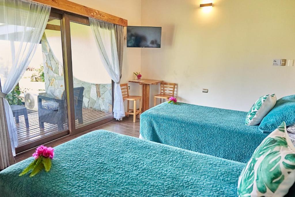 a hotel room with two beds and a balcony at Takarua Lodge in Hanga Roa