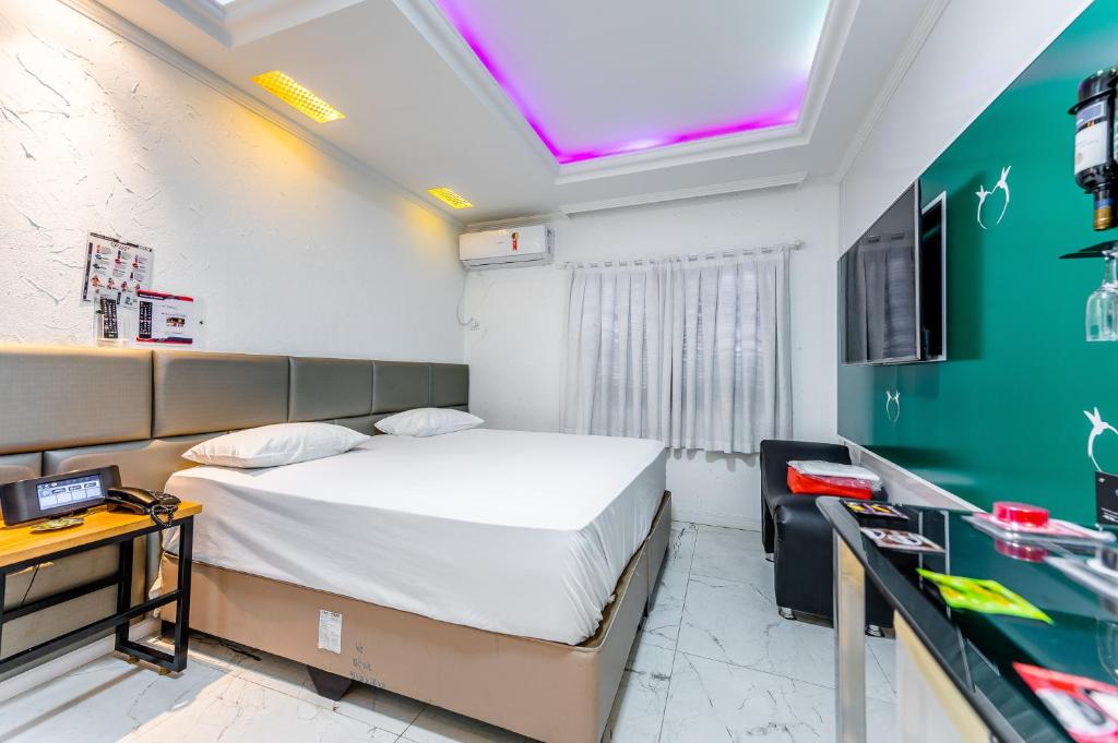 a hotel room with a bed and a desk and a tv at Amy Motel in Blumenau
