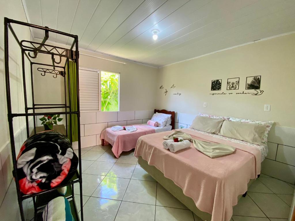 a bedroom with two beds in a room at Casa acolhedora ideal para famílias, com Wi-Fi rápido, cozinha exclusiva e equipada, varanda com churrasqueira - A apenas 1 km da praia do bairro e 5 km da charmosa Praia da Vila in Imbituba