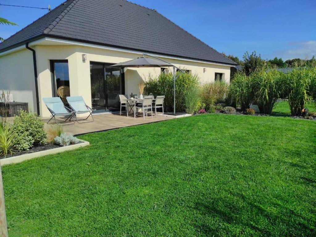 a house with a lawn with chairs and an umbrella at Gîte in Etretat near Cliffs & Beach in Bordeaux-Saint-Clair