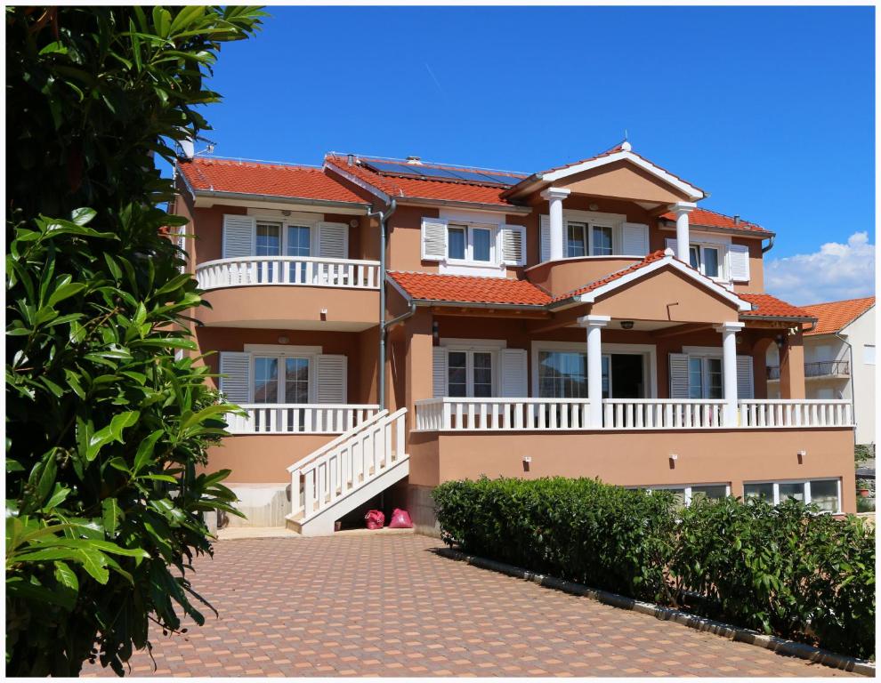 une grande maison avec une passerelle devant elle dans l'établissement Apartments Rupe, à Primošten