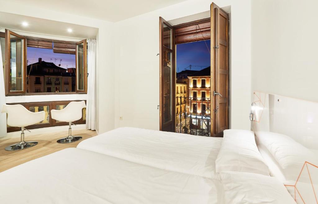 ein Schlafzimmer mit einem weißen Bett und einem großen Fenster in der Unterkunft AMC Granada in Granada