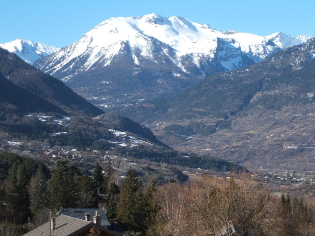 - une vue sur une chaîne de montagnes enneigée et une ville dans l'établissement Appartement Guillestre, à Guillestre