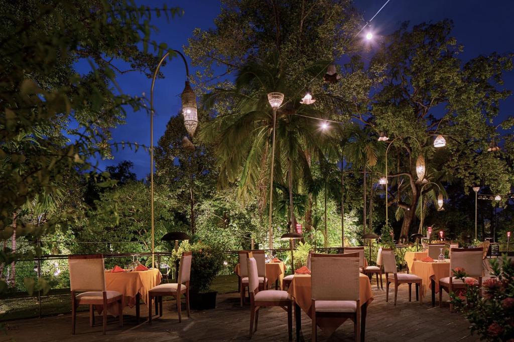 a restaurant with tables and chairs at night at Lynnaya Urban River Resort in Siem Reap