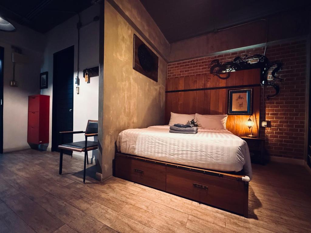 A dark wood bedroom with a raised bed, built-in drawers and a separate chair.