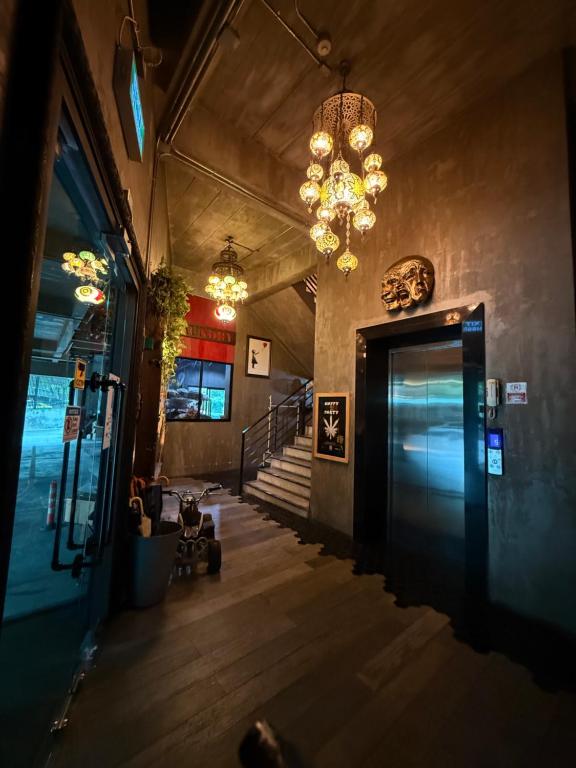 An atmospheric entrance hall with a glass-fronted lift, stairs and clustered pendant lights.