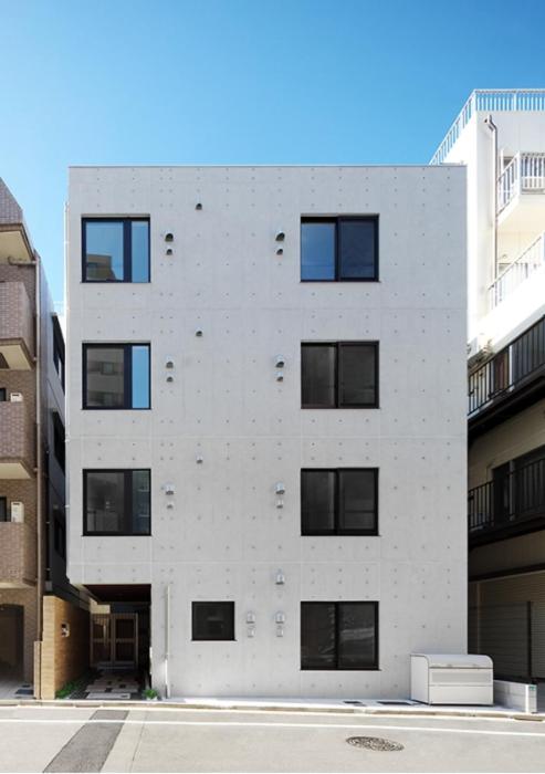a white building with black windows on the side of it at japan house Otsuka in Tokyo
