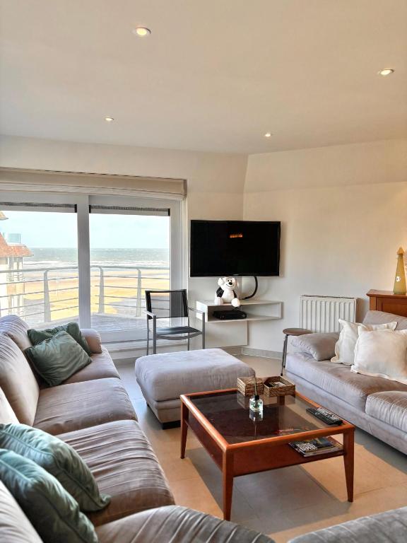 a living room with two couches and a table at Windjammer A3 - Sea View in Koksijde
