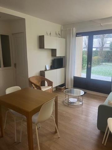un salon avec une table et des chaises et une cuisine dans l'établissement Appartement lumineux en rez-de- jardin, à Cabourg