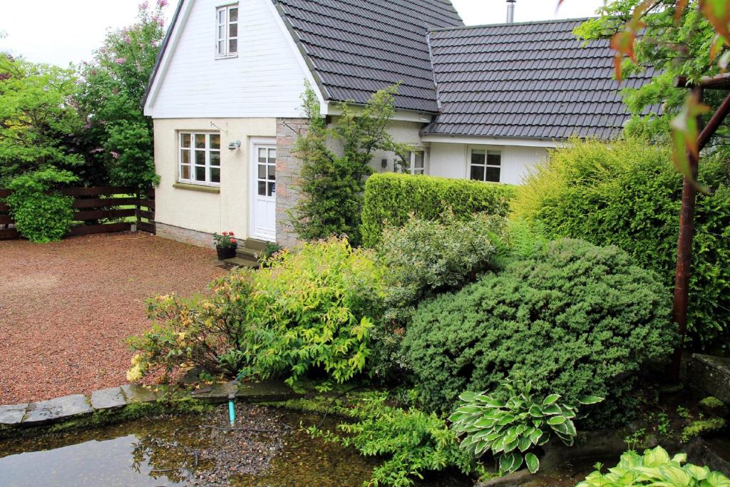 une maison avec un jardin et un étang en face de celle-ci dans l'établissement Westacre Lodge, à Auchterarder