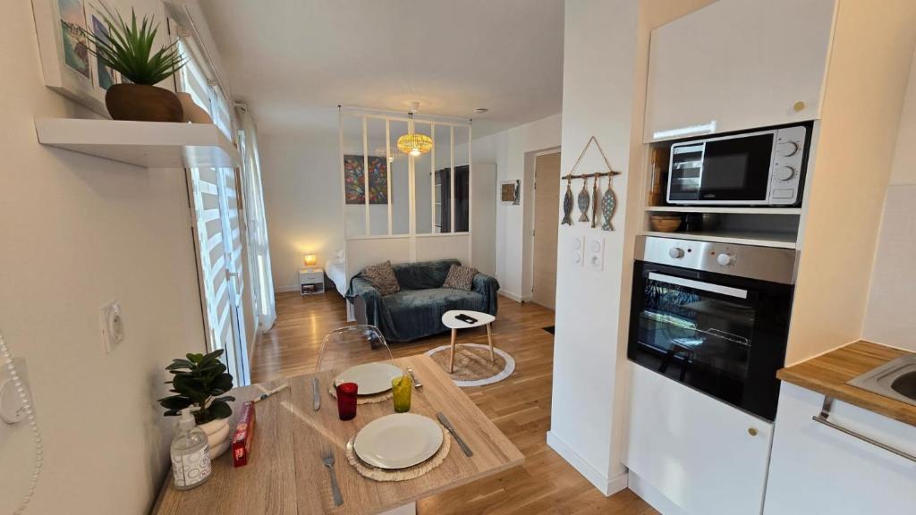 a kitchen and living room with a couch and a table at Vacances Ô Kastel - Studio Centre Ville proche de la mer in Fouesnant