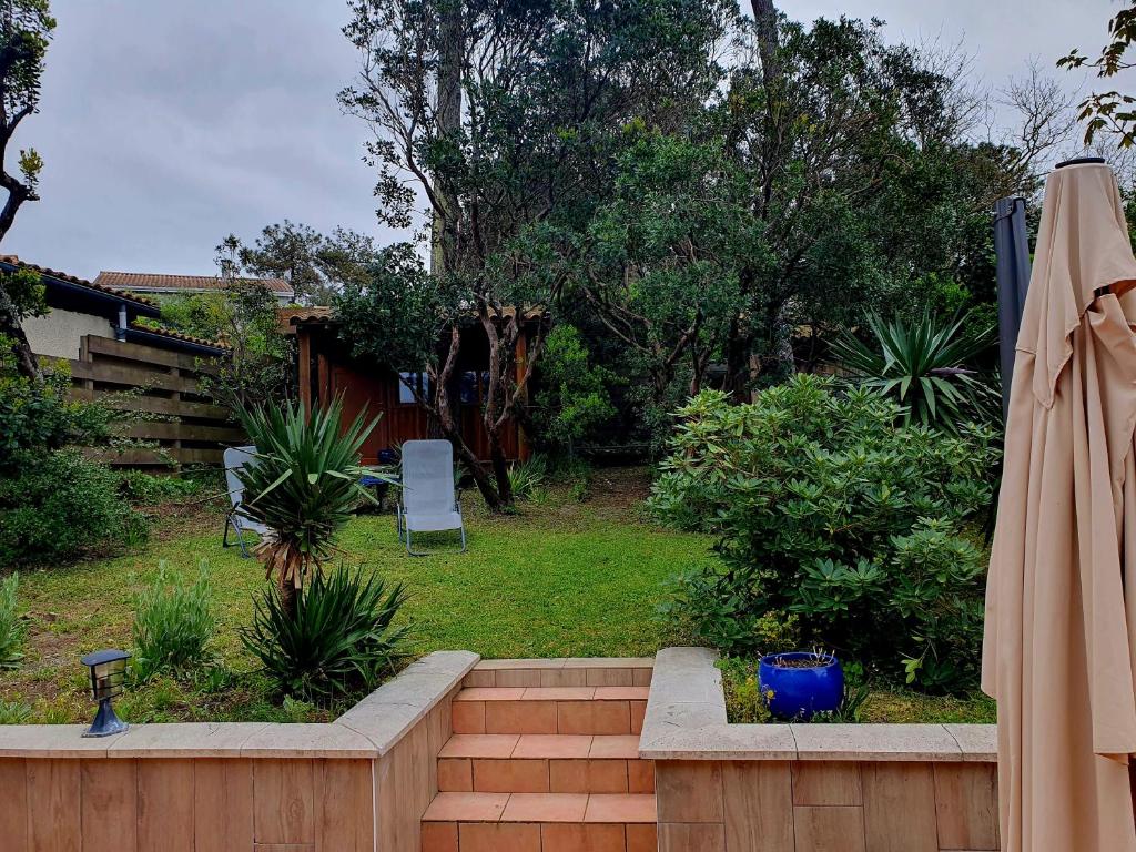 - un jardin avec un banc et un parasol dans l'établissement Villa familiale typique à Lacanau-Océan, à Lacanau