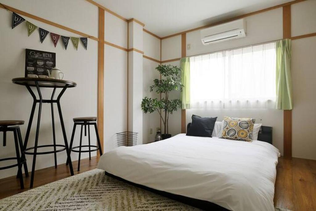 ein Schlafzimmer mit einem weißen Bett und einem Fenster in der Unterkunft Nakamichi House 中道戸建 in Osaka