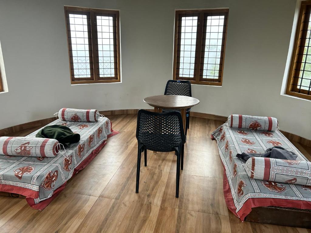 a room with two beds and a table and a chair at Heritage Farm Kerala in Idukki