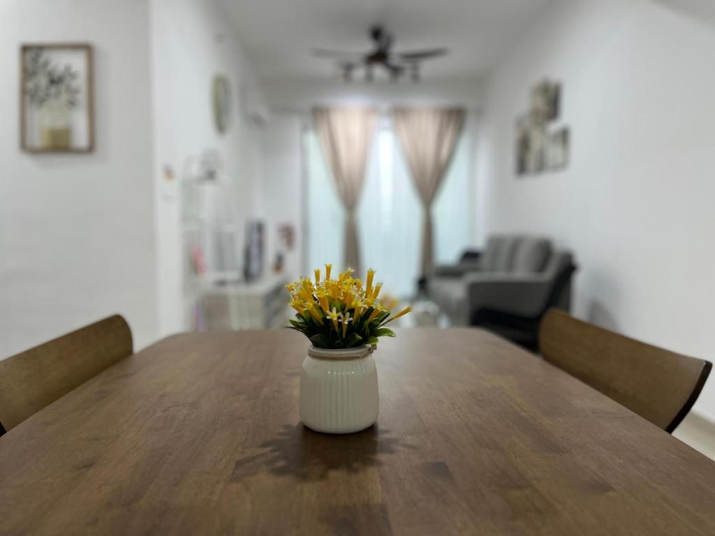 a vase with yellow flowers sitting on a wooden table at Humaira - Metropol in Bukit Mertajam