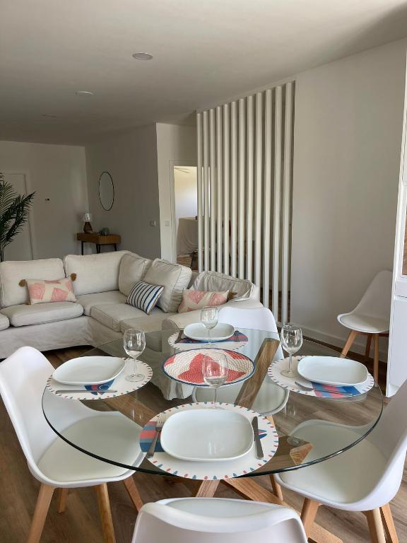a living room with a glass table and white chairs at Apartamento Tronqueiras in Praia da Vitória