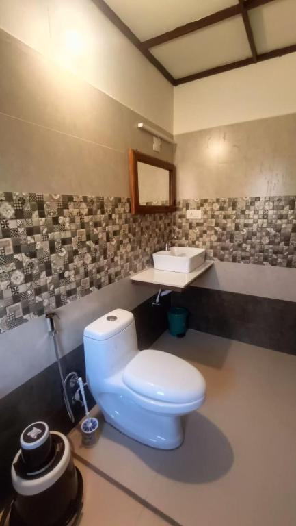 a bathroom with a white toilet and a sink at Heritage Farm Kerala in Idukki