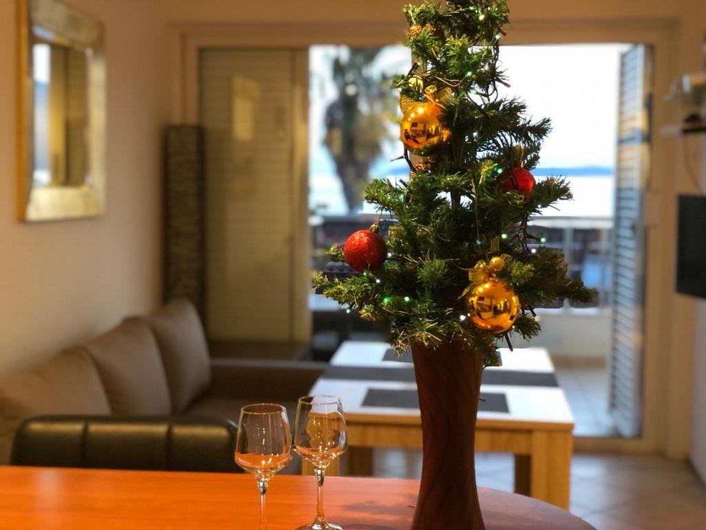 een kerstboom in een vaas op een tafel met wijnglazen bij Boka Residence 7 in Herceg-Novi