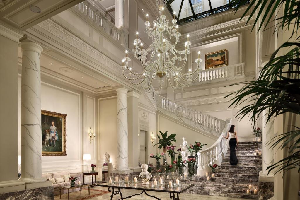 una donna che scende le scale in un edificio con un lampadario. di Palazzo Parigi Hotel & Grand Spa - LHW a Milano