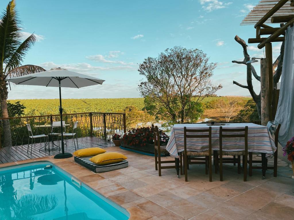a patio with a table and chairs next to a pool at Glamping do luxo - Tenda Curicaca in Delfinópolis